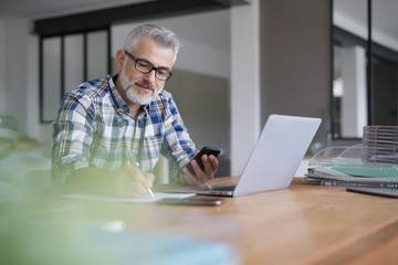 Man working from home with laptop and smartphone