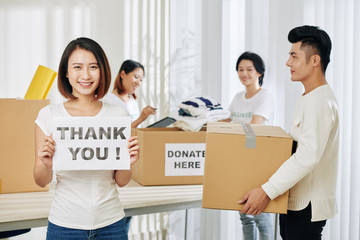 Sticker - Pretty young Vietnamese woman working as volunteer at donation center and showing thank young card