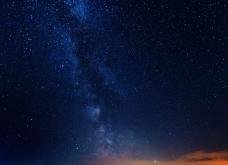 A magical starry night on the river bank with a large tree and a milky way in the sky and falling stars in the summer.	