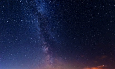 Wall Mural - a magical starry night on the river bank with a large tree and a milky way in the sky and falling st