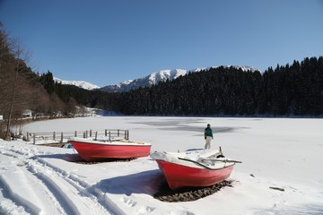 Two red wooden boats on a frozen lake.artvin