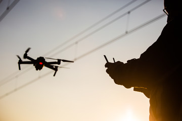 Wall Mural - man operating drone close to the electrical wire/ man holding remote control drones / drone controll