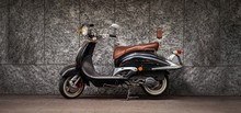 Black Scooter Parked In Front Of Gray Wall