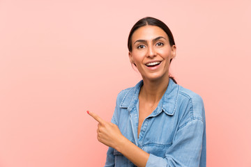 Young woman over isolated pink background pointing finger to the side