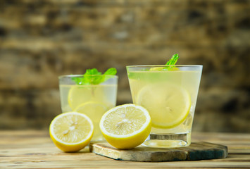 Wall Mural - Lemonade or mojito cocktail with lemon and mint on wood background