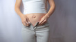 Pregnant woman is trying on her jeans or clothing that does not fit on her growing belly anymore in the first trimester