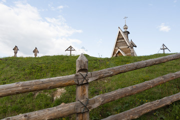 Wooden church and crosses on a hill on Volga river bank. Low angle picture. Summer tourism in Russia