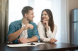 © studioprodakshn - young happy couple man and woman sitting in their new cosy apartment after successful real estate deal both smiling