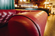 © gjeerawut - Closeup armrests of red leather classic sofa with blur reception hotel counter