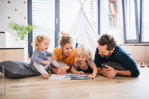 Cuadros en Lienzo Young family with two small children indoors in bedroom reading a book