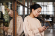 Image of young asian woman holding cellphone while working in office