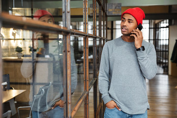 Wall Mural - Image of young african american man talking on cellphone in office