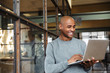 Image of bald african american man holding laptop while working in office