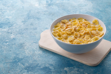 Breakfast with cereal. Flakes with milk. A plate of cereal with milk on a blue table. Perfect for breakfast. Free space for text.