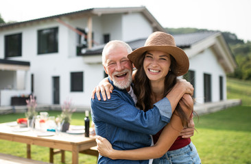 senior father with daughter outdoors in backyard, looking at camera.