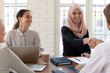 Poster - Smiling Arabian businesswoman handshake business partner at meeting