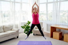Young Fitness Woman Doing Jumping Jacks Or Star Jump Exercise At Home, Copy Space. Girl Working Out, Full Length Portrait. Healthy Lifestyle Concept