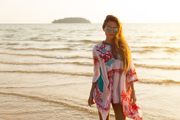 Wall Mural - Young lovely woman wearing beautiful dress is walking by the sea shore