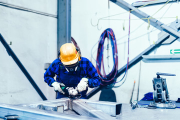 Wall Mural - Worker grinding in a workshop. Heavy industry factory