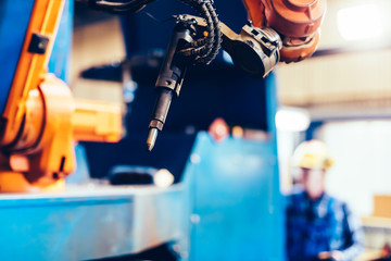 Wall Mural - Worker operating robotic arm to cut steel in a factory.