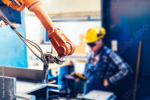 Fotomural Worker controls robotic arm to cut steel in a factory.