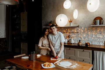 a young couple in love make dinner in the kitchen together. A man and a woman cook pizza together. Joint cooking