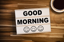 Lightbox Or Light Box With Happy Faces And Message Good Morning On A Wooden Table With A Cup Of Coffee