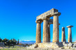 Ruins and columns at Ancient Corinth Greece under extremely blue sky with snow-capped mountains of the mainland across the Corinth Canal in the distance