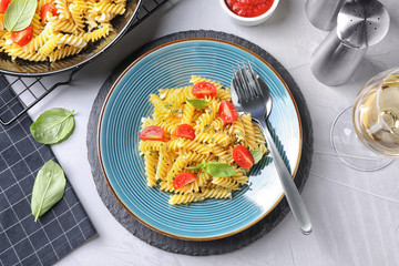 Wall Mural - Delicious pasta with tomatoes and basil served on light table, flat lay