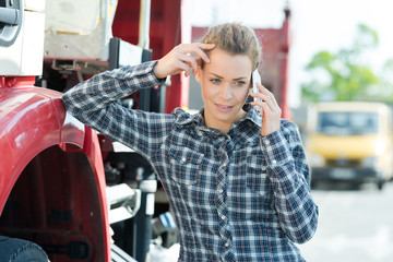 female driver talking by mobile phone next to modern truck