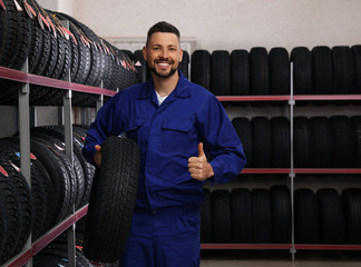 Canvas Print - Male mechanic with car tire in auto store