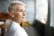 © shurkin_son - Close up profile shot of elegant short haired businesswoman wearing pearl earrings and stylish white blouse posing isolated in office interior, having pensive thoughtful look. Job, work and mature age