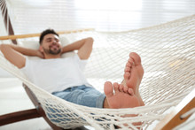 Young Man Relaxing In Hammock At Home, Focus On Feet