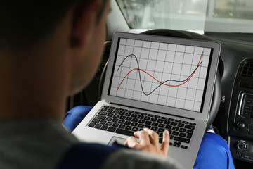 Poster - Mechanic with laptop doing car diagnostic at automobile repair shop, closeup