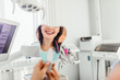 © Тарас Нагирняк - Cropped image, woman is holding a mirror for looking through the final work of dental doctor.