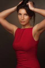 portrait of a brunette on a gray studio background in a red dress