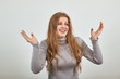 © Petro - a young beautiful red haired woman in gray sweater is happy raises her hands up and smiles