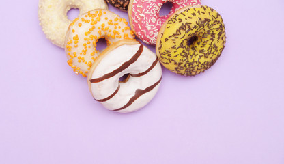 Delicious donuts on violet color background.