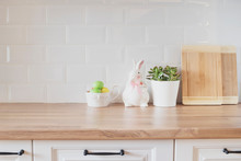 Easter Eggs, Rabbit, Cutting Boards, Succulent On The Kitchen Counter. Bright And Clean Rustic Kitchen With White Cabinets, Close Up. Kitchenware In Modern Kitchen Interior. White Tiles 