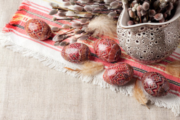 Wall Mural - Easter still life with Pysanka and willow branches in ceramic jug on traditional Ukrainian cloth. Decorated Easter eggs, traditional for Eastern Europe culture