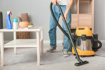 Sticker - Young Asian man hoovering floor at home