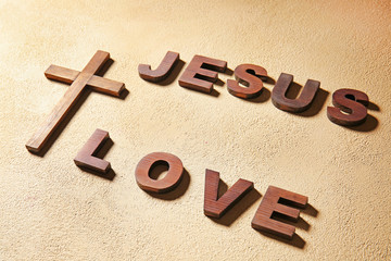 Christian cross and text JESUS LOVE on color background