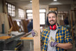 Portrait of handsome smiling carpenter with wood material at workshop holding thumbs up. Do it yourself concept. Creativity concept.
