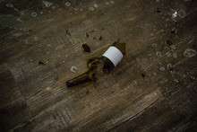 Broken Brown Beer Bottle With White Sticker On The Wooden Floor.