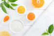 Natural homemade cosmetics: scrub, cream and sea salt with orange fruit on white background. Organic beauty or SPA concept. Flat lay, top view.