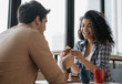 © ARUTA Images - Young lovely couple laughing, sitting in cafe. Beautiful emotional African American woman eating tasty cake. Happy multiracial friends communication together. First date concept