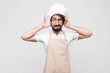 young crazy chef feeling stressed, worried, anxious or scared, with hands on head, panicking at mistake against white wall