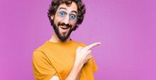 Young Crazy Cool Man Looking Excited And Surprised Pointing To The Side And Upwards To Copy Space Against Flat Wall