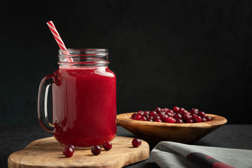 Poster - Healing cranberry juice in a glass jar-mug with a straw on black table. Healthy eating concept with copy space