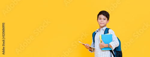 Cuadros en Lienzo Handsome schoolboy with backpack holding books and tablet computer on banner bac